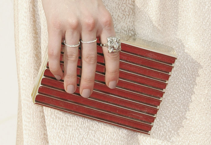 Emma Roberts shows off a nude manicure and several sparkling rings as she holds a red clutch