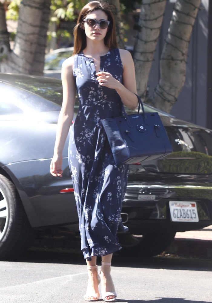 Emmy Rossum struts across a parking lot in an all-navy outfit