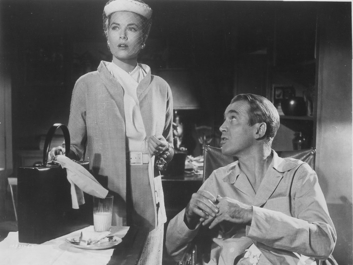 Grace Kelly as Lisa Fremont stands poised with the overnight case that later inspired the iconic Mark Cross “Grace” trunk bag, beside James Stewart as L.B. "Jeff" Jefferies in Alfred Hitchcock’s Rear Window (1954)