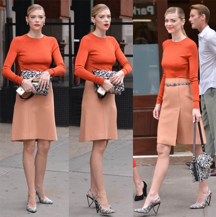 Jaime King stuns in an orange sweater and peach A-line skirt, accessorized with a printed belt, pumps, and an embellished bag during New York Fashion Week