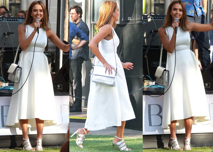 Jessica Alba grabs a microphone and participates in an interview while wearing a white dress
