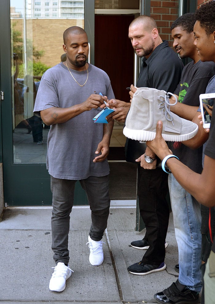 Rapper Kanye West pauses to sign autographs during a New York City walk with his wife, Kim Kardashian