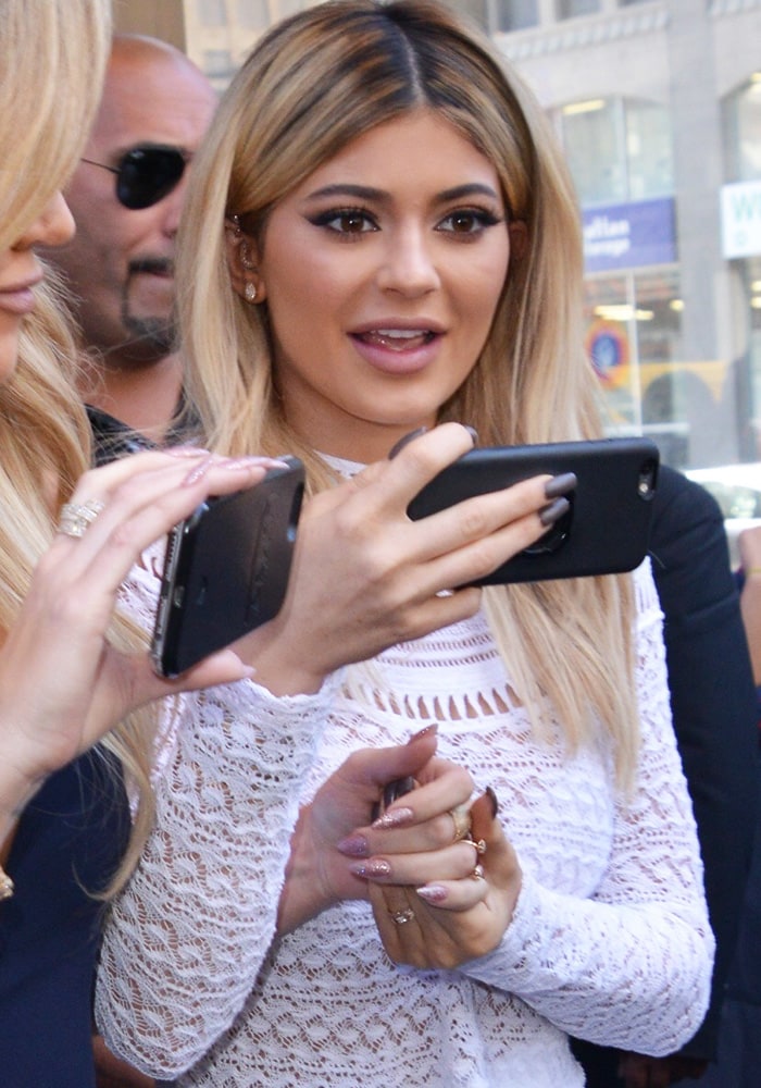 Kylie Jenner takes a video of the paparazzi as she leaves her New York hotel on September 15, 2015