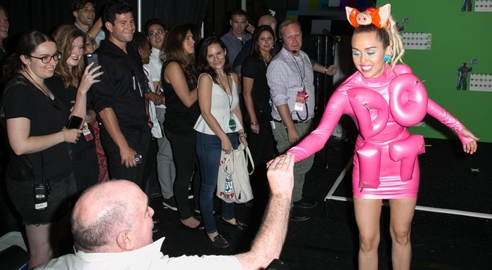 Miley Cyrus offers a joint to reporters as she goofs around backstage at the MTV VMAs