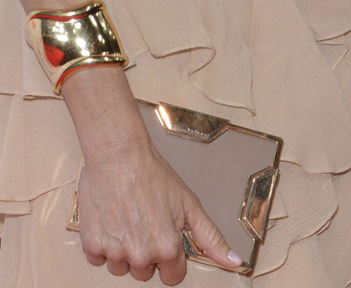 Naomi Watts grasps a box clutch from Lee Savage and flaunts one of her two gold cuffs from Tiffany & Co.