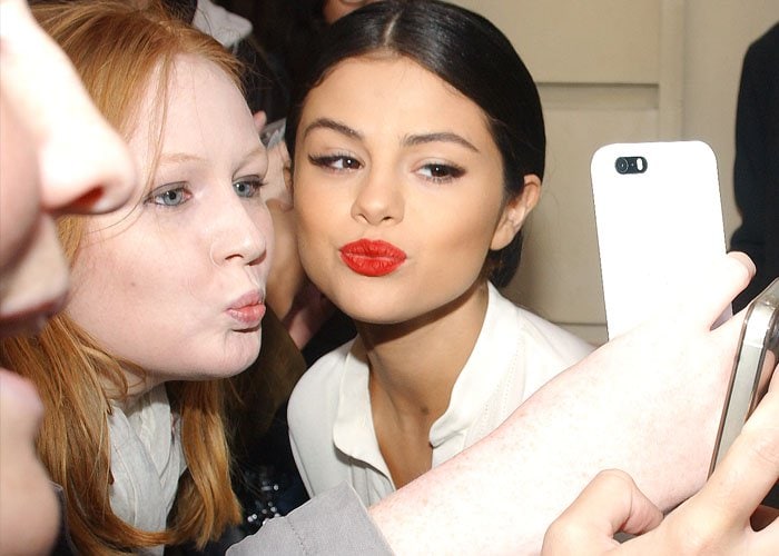 Selena Gomez shows off her dramatic eyeliner and red lipstick as she takes a selfie with a fan