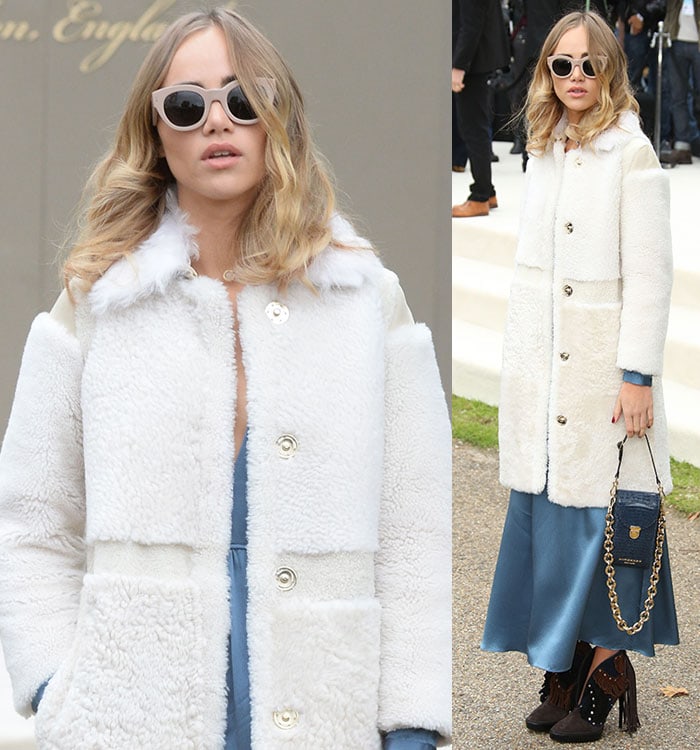 Suki Waterhouse covers her eyes with large sunglasses and holds a blue bag in her hands at London Fashion Week