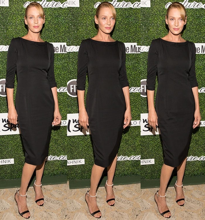 Uma Thurman wears a simple black dress as she poses against a green backdrop