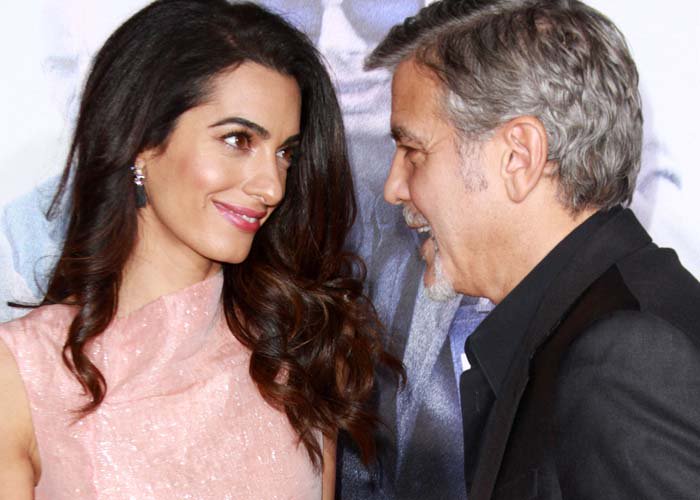 Amal Clooney and George Clooney smile at each other on the red carpet