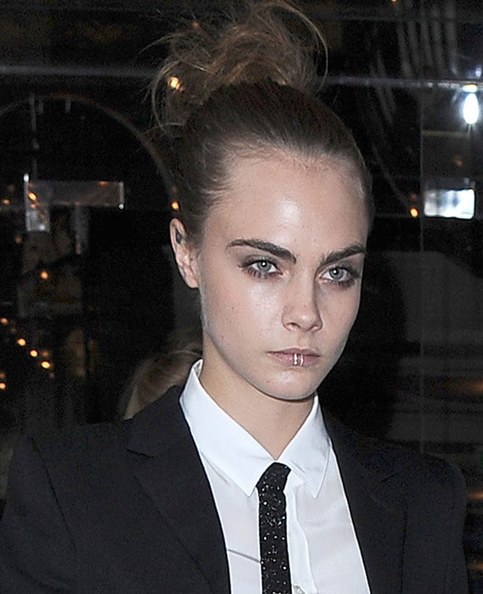 Cara Delevingne exudes edgy sophistication in a monochrome Saint Laurent suit paired with a glittery tie and bold lip ring