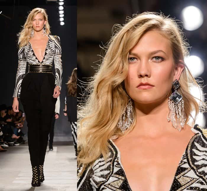 Karlie Kloss exudes elegance in a deep V-neck Balmain x H&M jumpsuit, accented with bold crystal earrings and a cinched waist