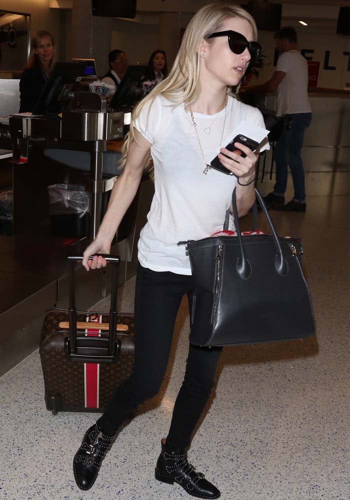 Emma Roberts wears her blonde hair down as she strolls through LAX with a suitcase