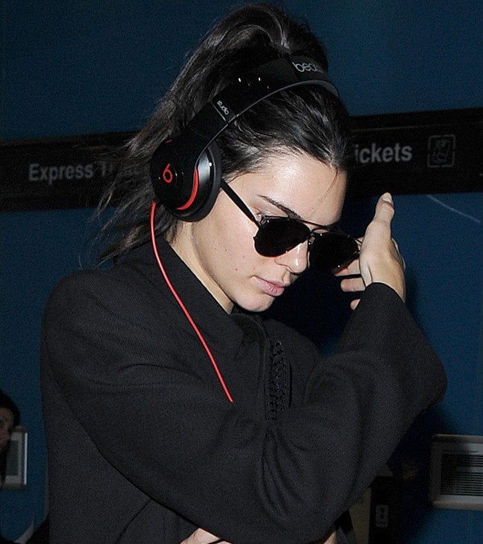 Kendall Jenner shields her face from the cameras as she arrives at Heathrow Airport