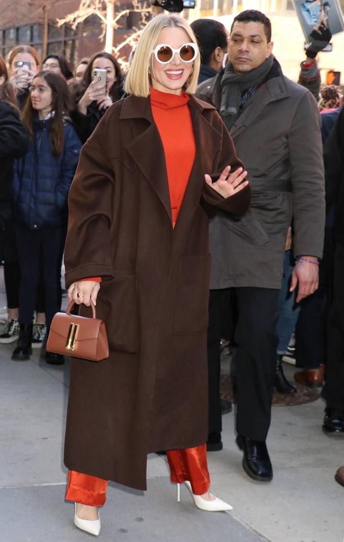 Kristen Bell wearing a Nanushka coat with a top and pants from Bouguessa, Jennifer Fisher jewelry, a DeMellier ‘Montreal’ bag, Lapima sunglasses, and Jimmy Choo shoes