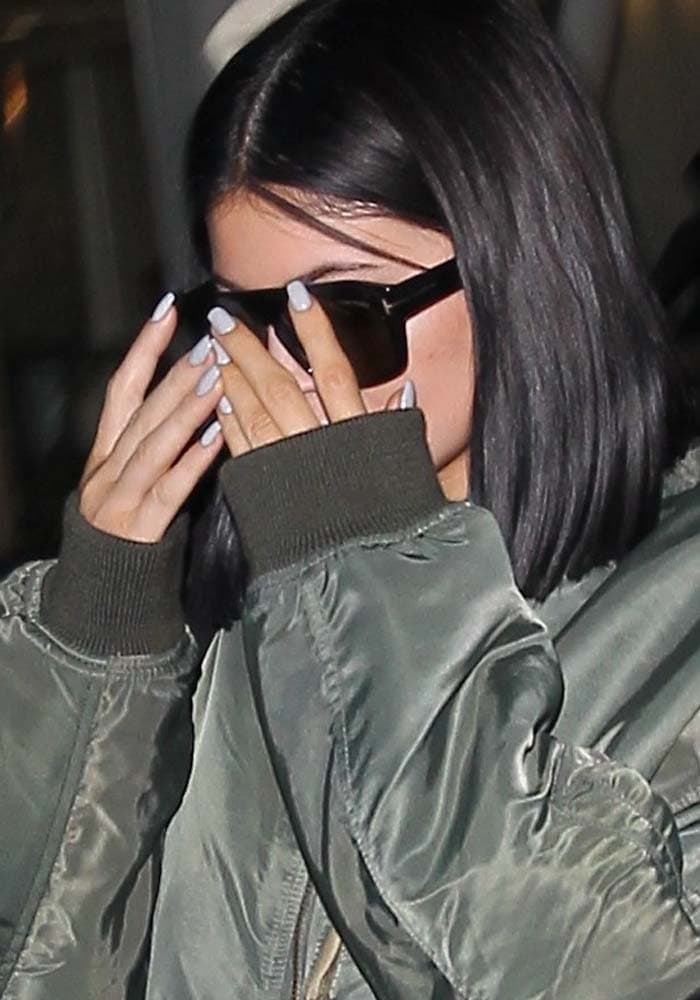 Kylie Jenner covers her face with Tom Ford sunglasses as she arrives at Los Angeles International Airport