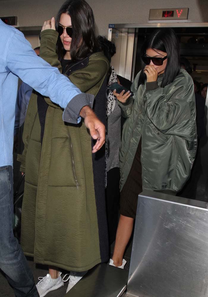 Kendall Jenner and Kylie Jenner both wear olive-colored ensembles as they make their way through LAX