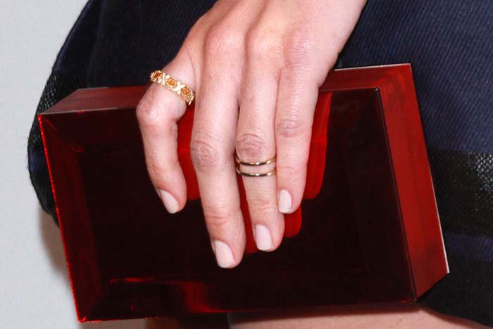 Olivia Munn flaunts her elegant manicure while accessorizing with a striking red acrylic clutch and delicate gold rings