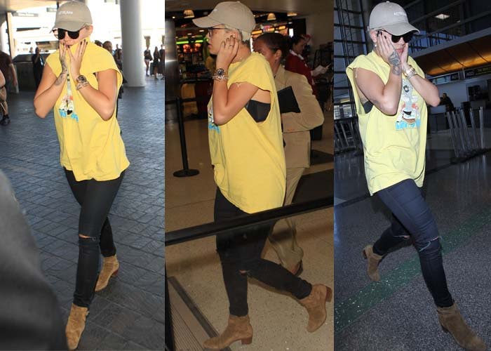 Rita Ora touches her face and shows off her hand tattoos as she strolls through London's Heathrow Airport