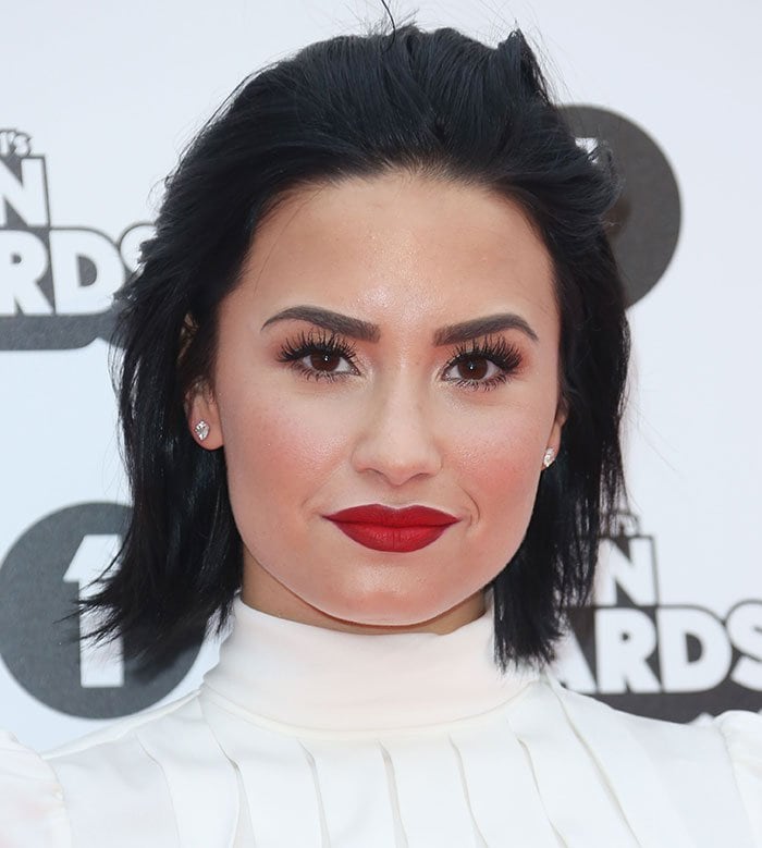 Demi Lovato wore her jet-black locks down and sported flawless makeup with lashings of mascara, defined eyebrows, and red lipstick
