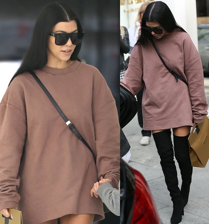 Kourtney Kardashian covers her eyes with a large pair of black sunglasses