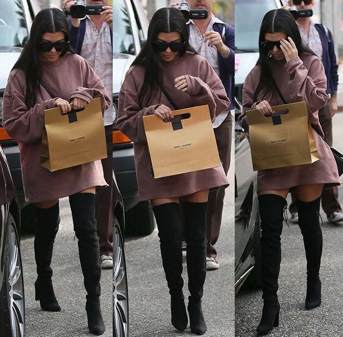 Kourtney Kardashian shields her face from the paparazzi as she walks through Los Angeles in a pair of over-the-knee boots