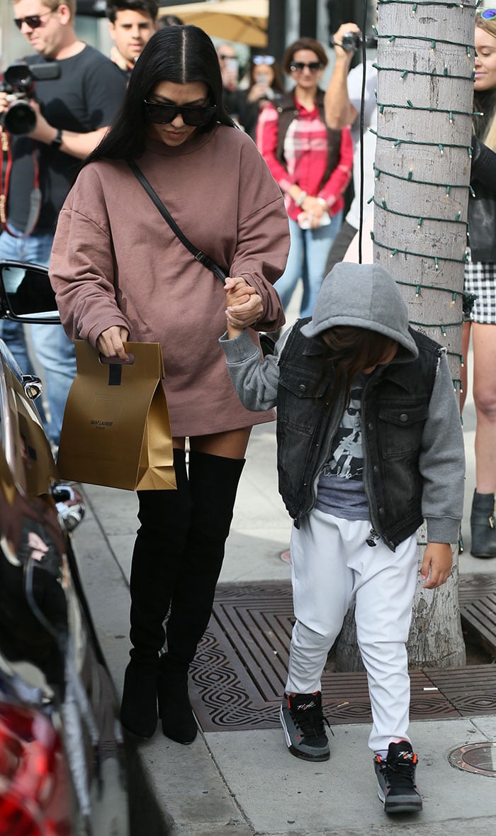 Kourtney Kardashian wears an oversized Yeezy sweater and a pair of over-the-knee Stuart Weitzman boots on a Los Angeles outing