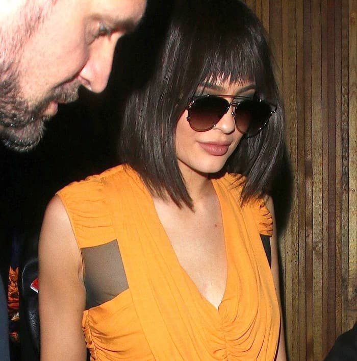 Kylie Jenner, wearing a short brunette wig featuring a blunt fringe, smoky eyewear, and large false lashes, leaves The Nice Guy in West Hollywood after Kendall's Birthday Celebration Party