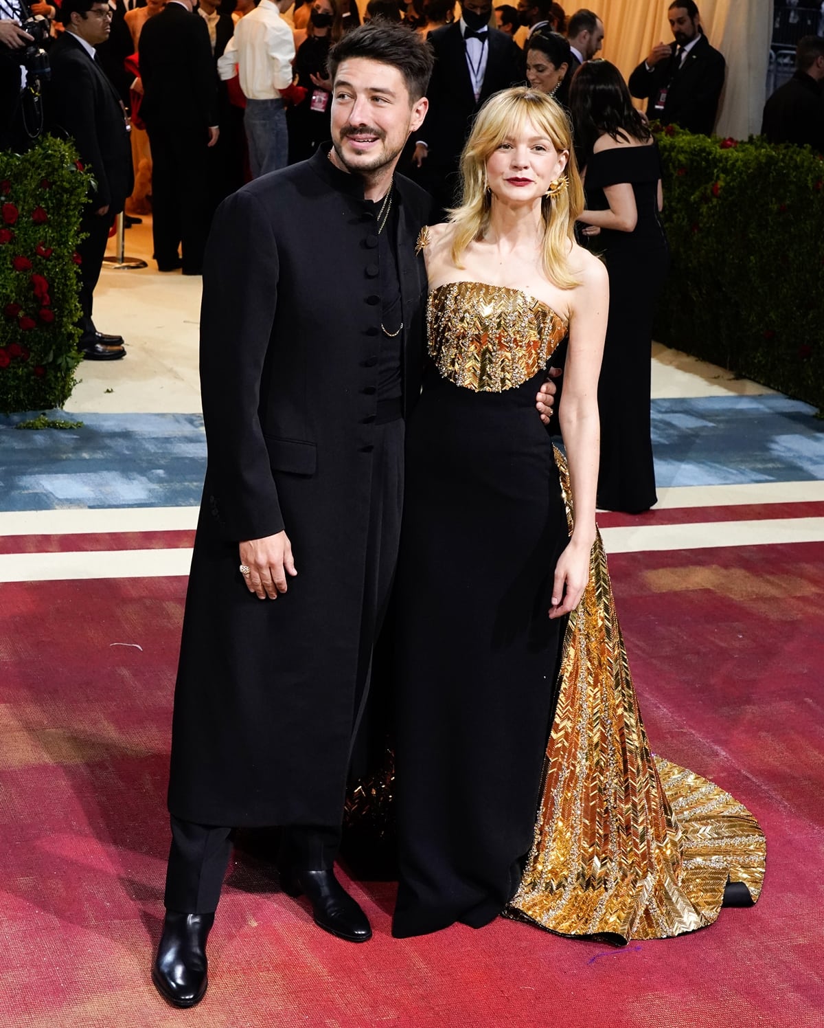 Marcus Mumford and Carey Mulligan made a striking pair at the 2022 Met Gala, with Marcus in a sleek black long coat and Carey dazzling in a regal strapless black gown adorned with shimmering gold embroidery and a dramatic metallic train