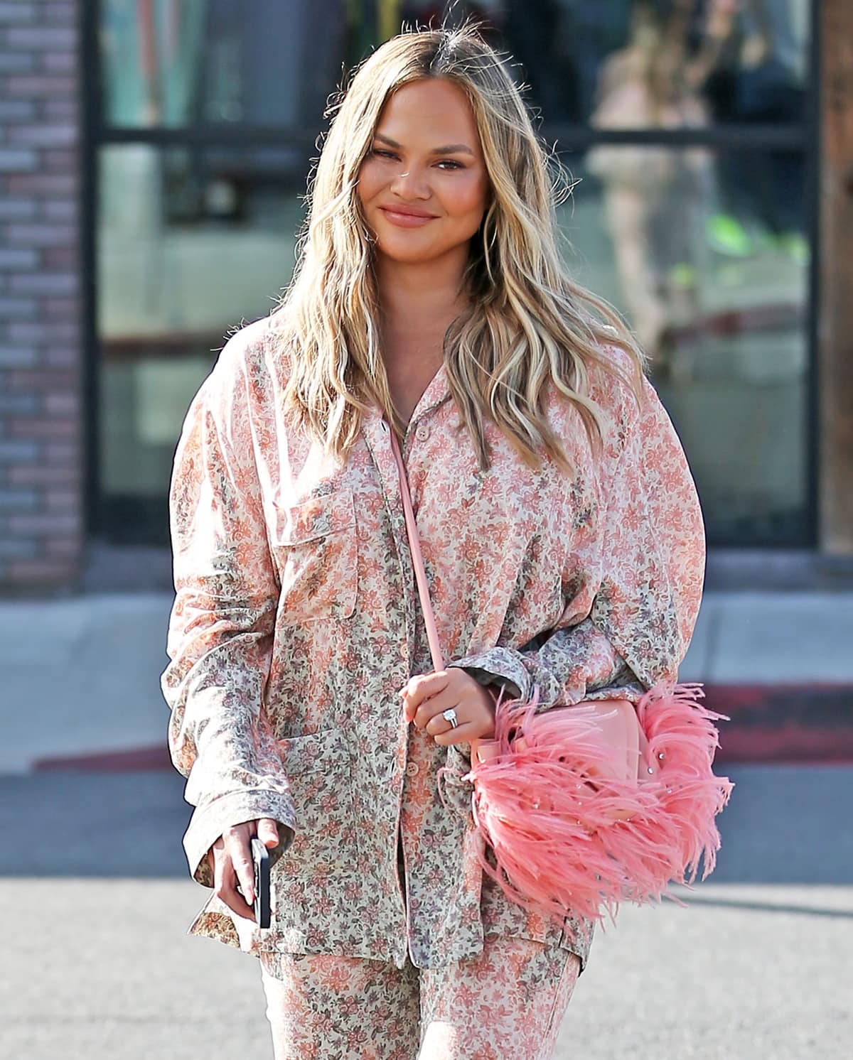 Chrissy Teigen wears a beige and red oversized floral shirt in a gradient color palette