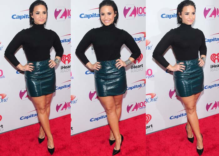 Demi Lovato turns heads in a sleek black roll-neck jumper, a crocodile-textured emerald mini skirt from Topshop Unique, and sharp black Versace stiletto pumps