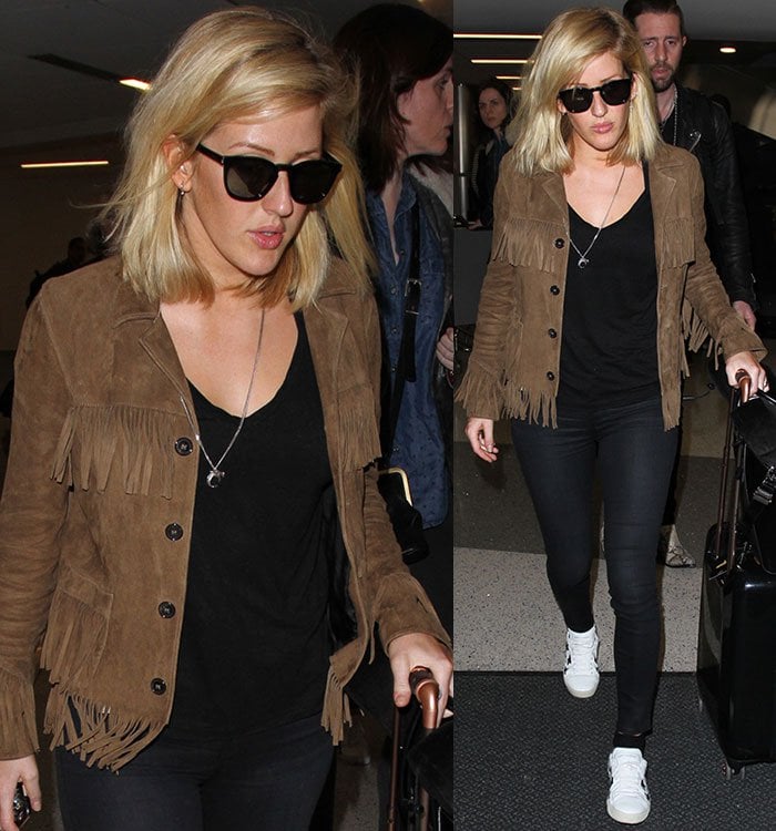 Ellie Goulding covers her eyes with a pair of dark sunglasses as she rolls her suitcase through LAX