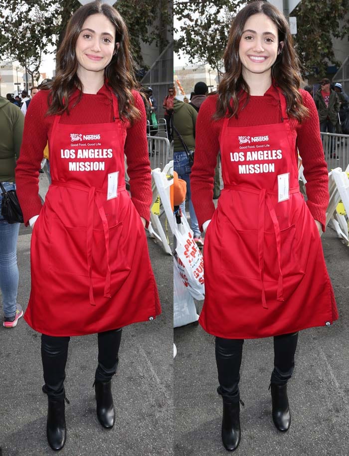 Emmy Rossum wears a red sweater underneath her LA Mission hat and apron