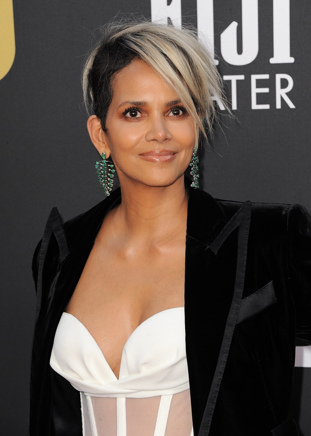 Halle Berry styles her suit with a white see-through Mônot Resort 2022 corset top with Samer Halimeh emerald earrings