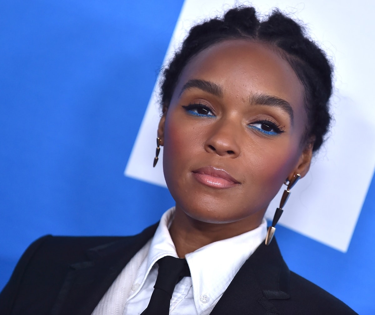 Janelle Monáe pairs a sleek tailored suit with vibrant electric blue eyeliner and modern geometric earrings for a striking, contemporary look