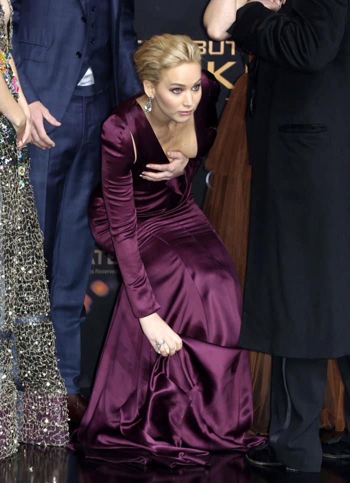 Jennifer Lawrence quickly adjusts her dress hem at 'The Hunger Games' premiere