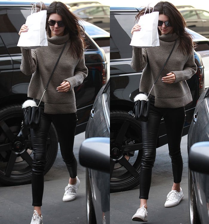 Kendall Jenner covers her face with a bag in an Aritzia turtleneck sweater and Helmut Lang leather pants