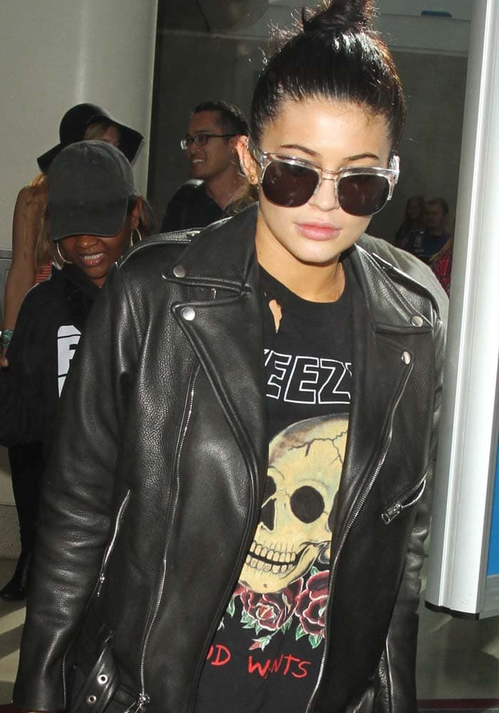 Kylie Jenner covers her eyes with a pair of sunglasses as she arrives at LAX