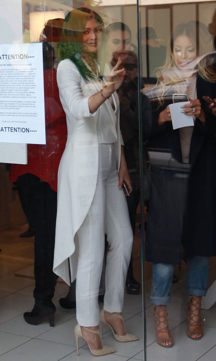 Kylie Jenner wears an all-white ensemble and waves at fans during the launch of her lip kit collection in West Hollywood