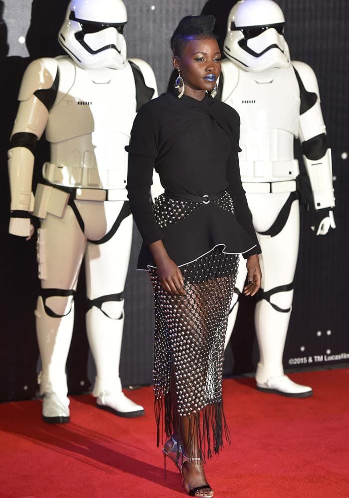 Lupita Nyong'o wears a Proenza Schouler dress as she poses on the red carpet in front of Stormtroopers