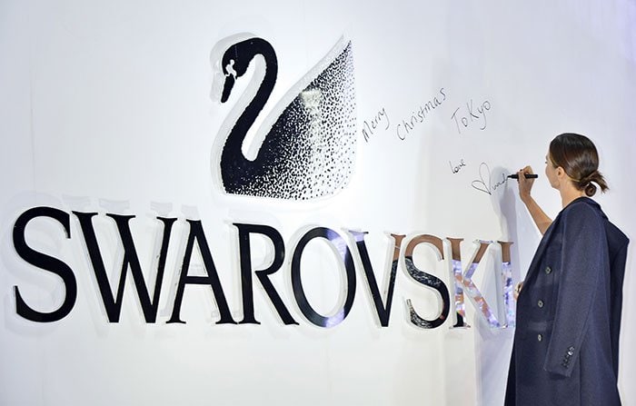Miranda Kerr signs a wall in the Sony Ginza building during the launch of her new Swarovski collection