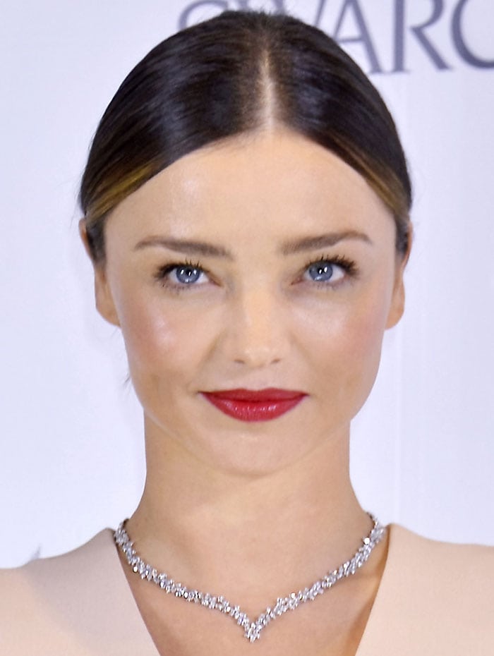 Miranda Kerr with red lipstick wears her dark hair back at a press conference for her jewelry collection launch