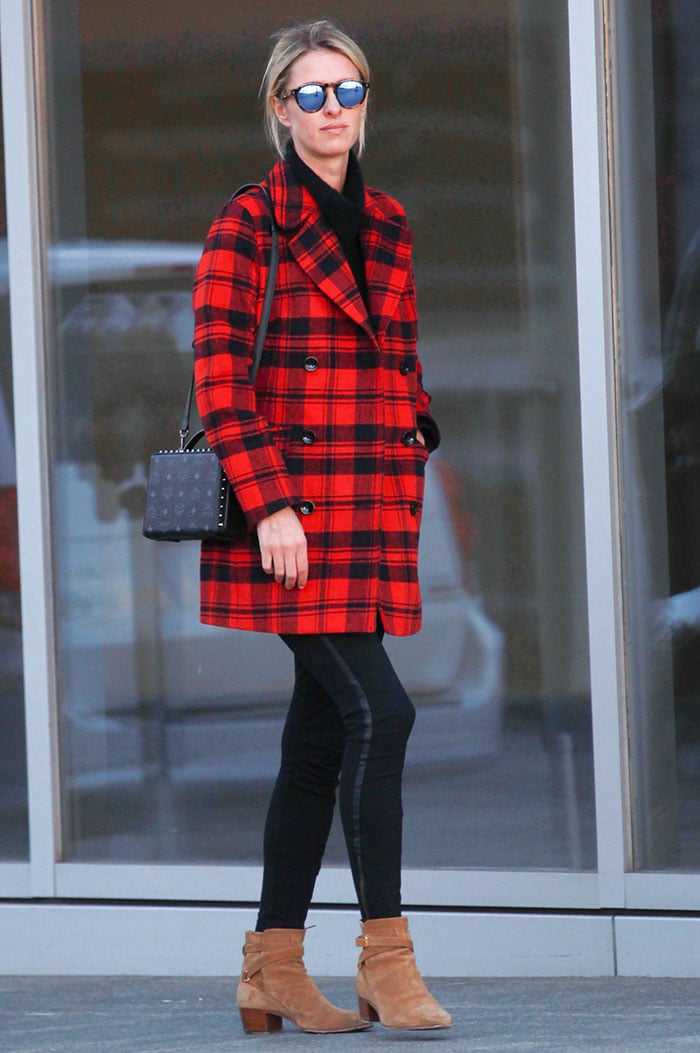 Nicky Hilton wears a red-and-black plaid coat over a pair of black leggings while out shopping