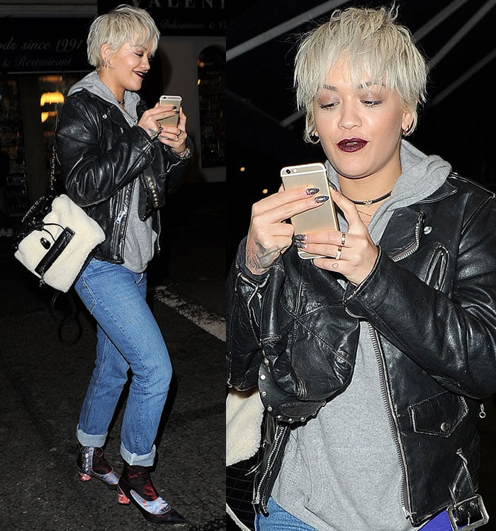 Rita Ora checks her phone while wearing a leather jacket from Acne Studios
