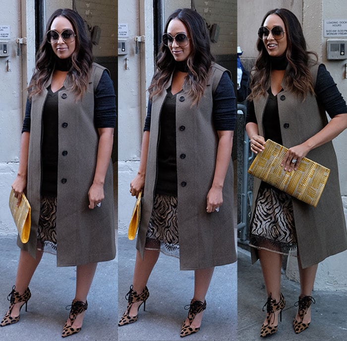 Tia Mowry carries a colorful clutch and wears a pair of large sunglasses