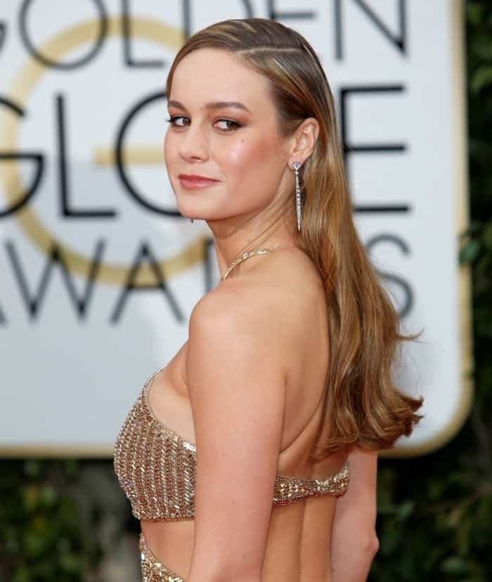 Brie Larson exudes elegance in a close-up of her shimmering gold Calvin Klein Collection gown, with sleek, side-parted hair and delicate diamond earrings, at the 2016 Golden Globe Awards