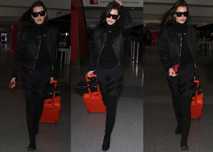 Bella Hadid departs from LAX in an all-black ensemble with a bright orange suitcase