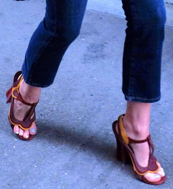 Chloë Grace Moretz steps confidently in her statement-making sandals, featuring a bold red-and-yellow design with T-straps and sculpted chunky heels