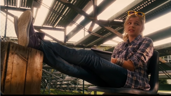 Chloë Grace Moretz relaxes in casual style, sporting a plaid shirt, jeans, and sunglasses, while kicking back with her feet up in a pair of classic Converse sneakers as reporter Angie Steadman in Diary of a Wimpy Kid