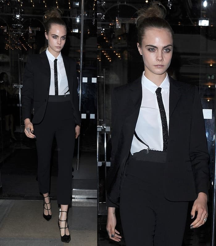 Cara Delevingne exudes cool sophistication in a sharp black suit paired with a white shirt and bold lip ring, effortlessly blending edgy and chic