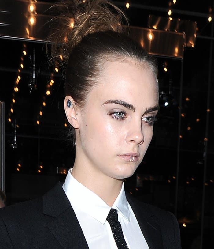 Cara Delevingne shows off her edgy style with a sleek lip ring and a sharp, tailored look, adding a rebellious touch to classic elegance